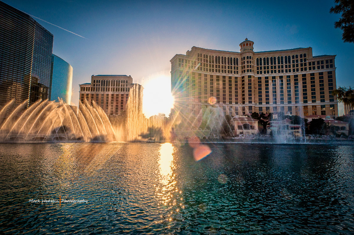 Sunset over the Bellagio fountains with water jets spraying in front of iconic Las Vegas hotels.